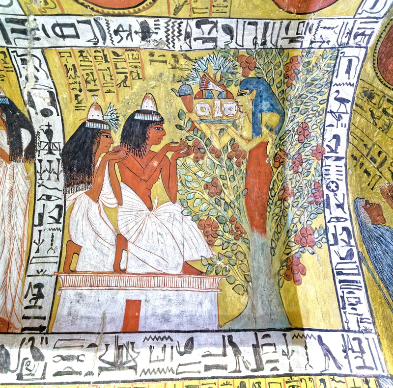 Tomb painting: a goddess with blue hair rises from a leafy tree heavy with red fruit and holds out a tray of offerings and a spouted vessel to a seated man and woman
