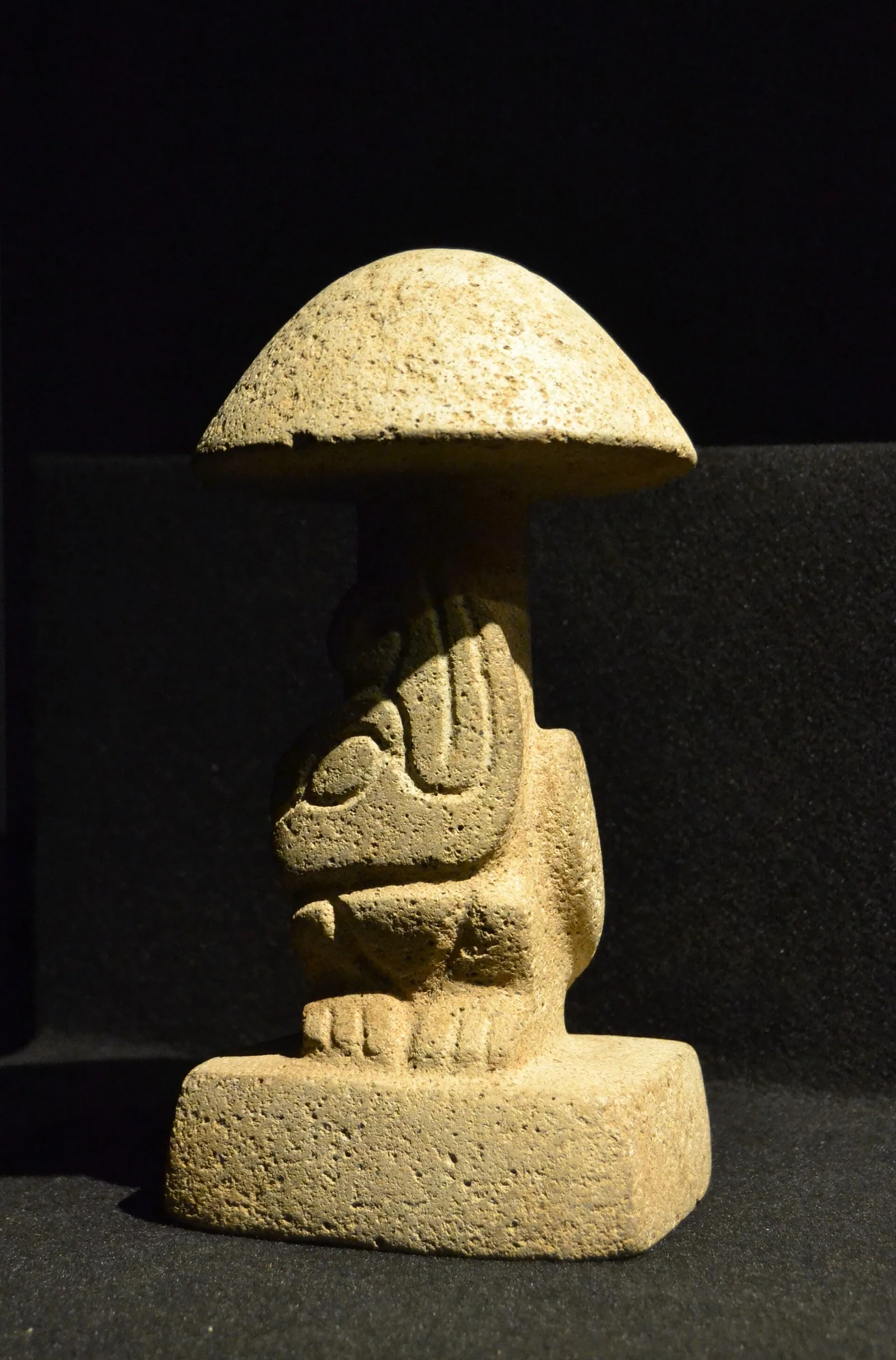 A mushroom-form sculpture in basalt from Kaminaljuyú, Late Preclassic. Borhegyi excavated nine such miniatures at the site’s Verbena cemetery, cached with nine miniature metates and handstones. The grinding equipment is the evidence; the ceremony is the inference.