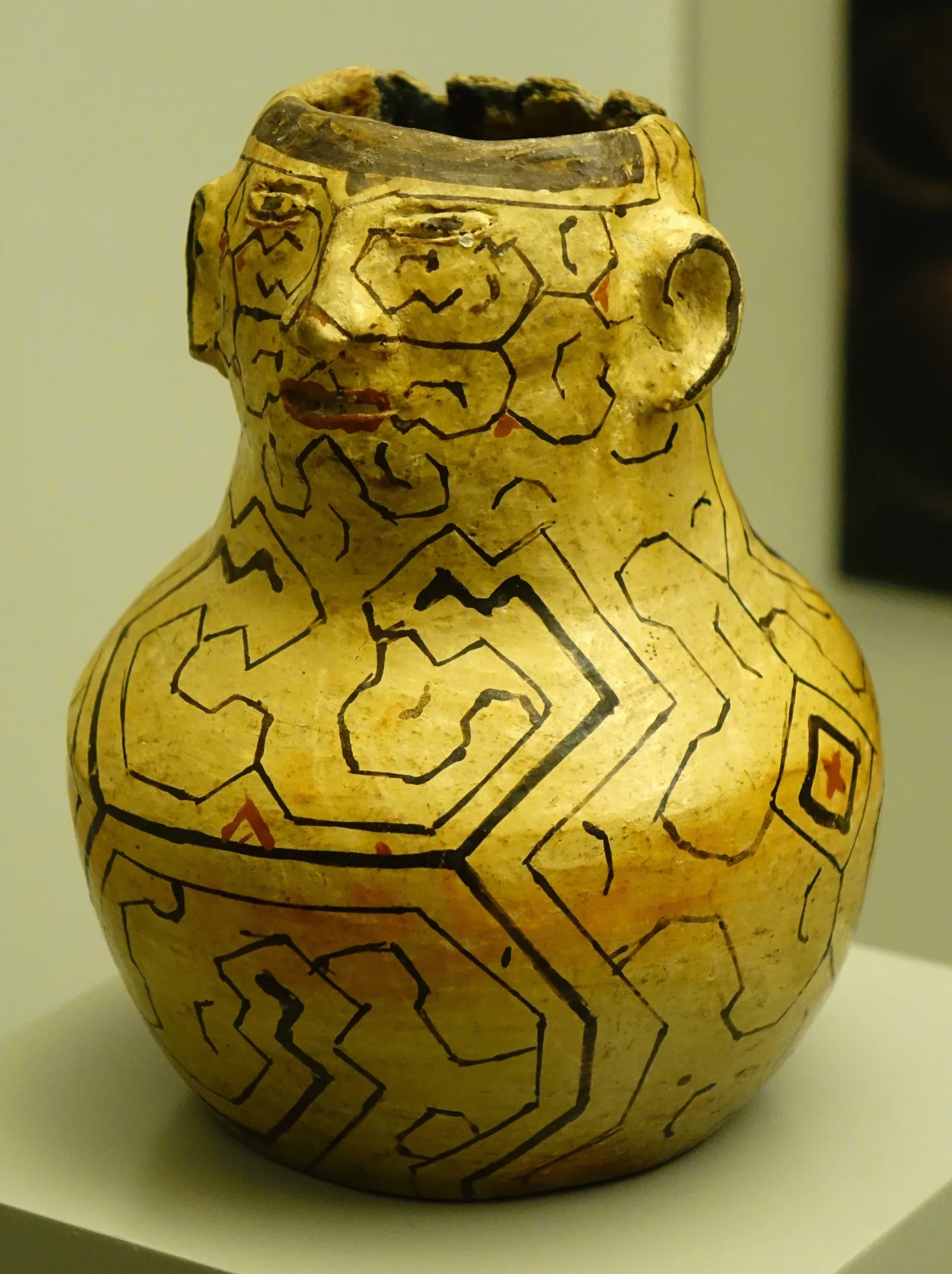 Joni chomo: a small Shipibo ceramic vessel with a modelled human face at the neck, its whole surface painted with black linear designs on a yellow ground. Museo de América, Madrid.