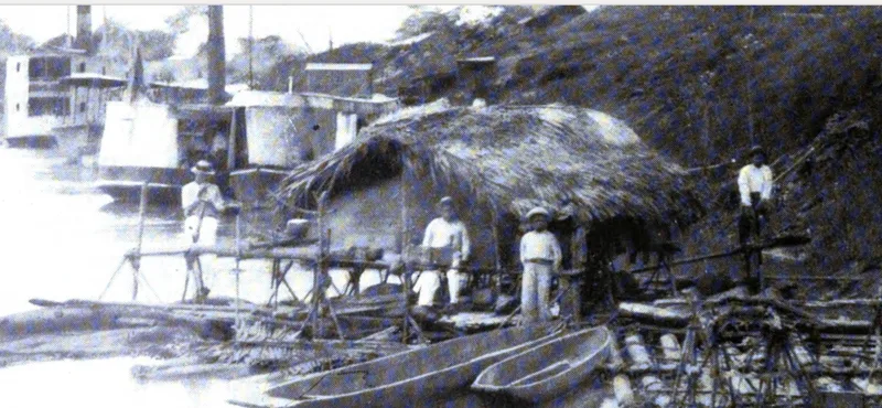 “Native raft and canoes used for rubber transport at Iquitos”: men on a thatched raft moored among dugout canoes, river steamers behind. Photograph published in 1913.