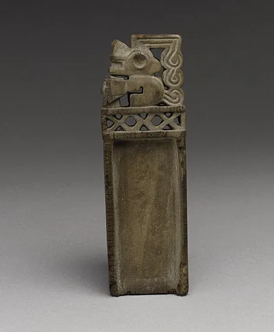 A narrow wooden snuff tablet with a shallow tray and a carved zoomorphic figure and lattice at its upper end