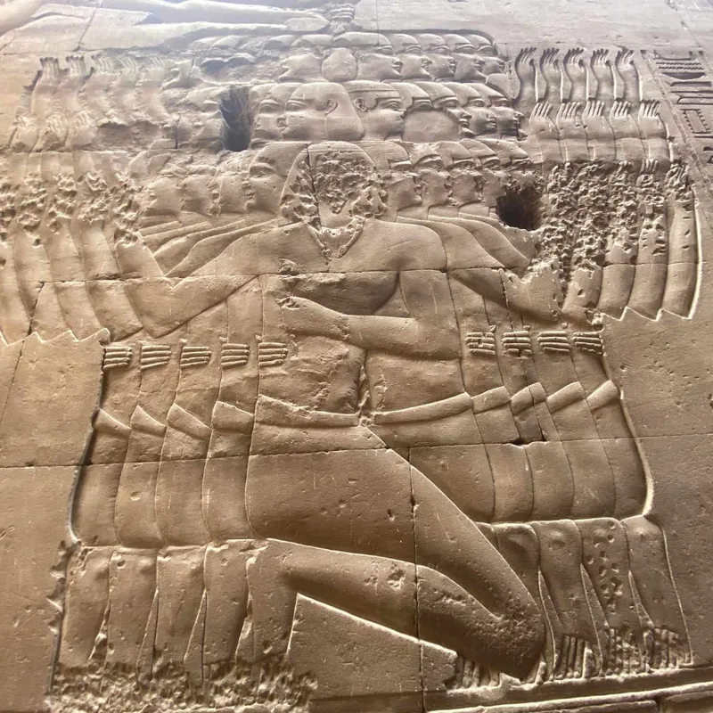 Temple relief: a kneeling figure repeated in overlapping outline, so that rows of heads, raised hands and arms rise from a single body